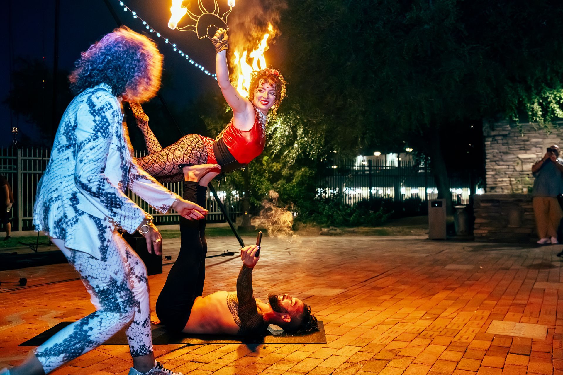 A group of people are performing a fire show in a park at night.