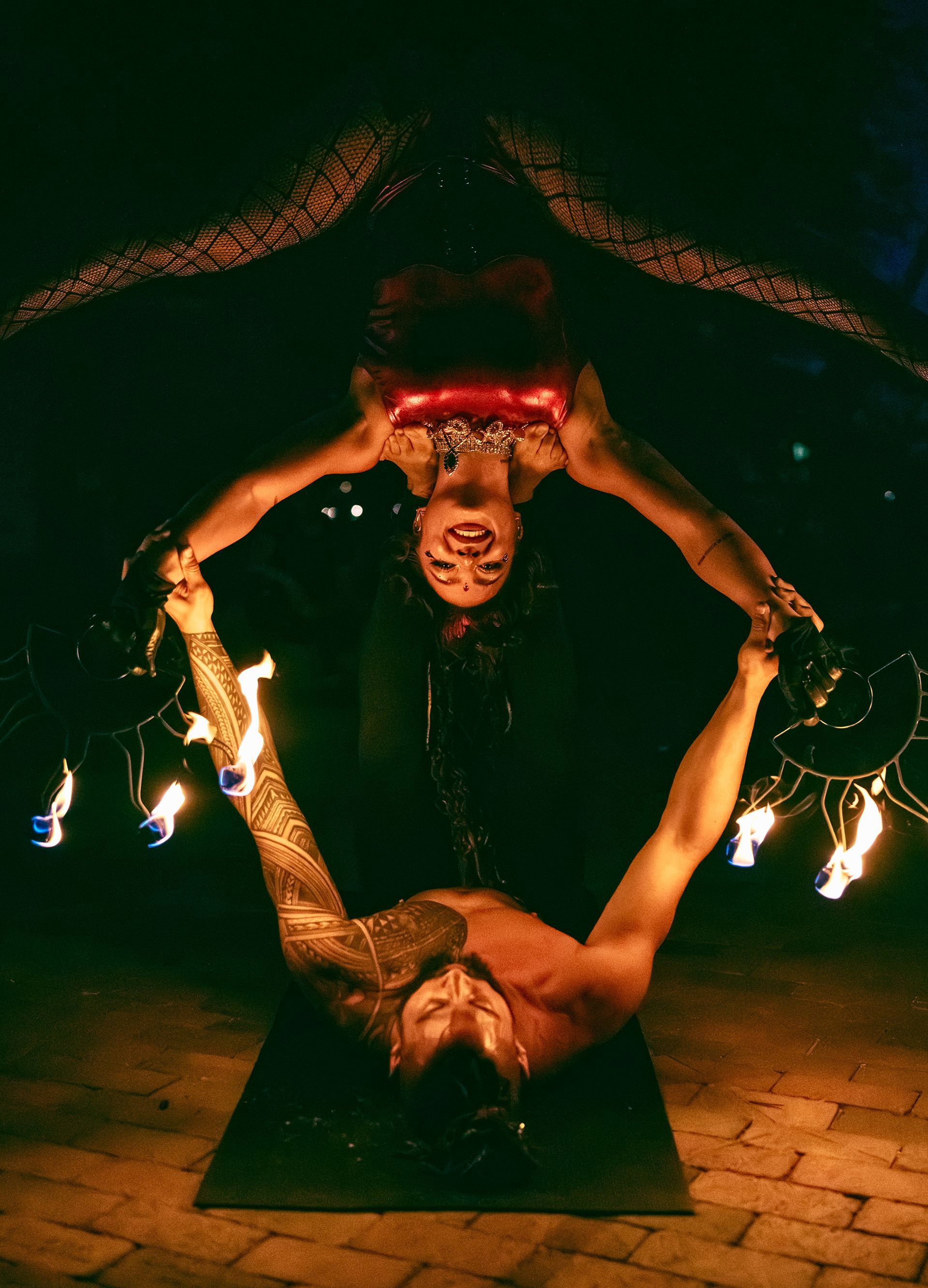 A man and a woman are doing a stunt with fire.