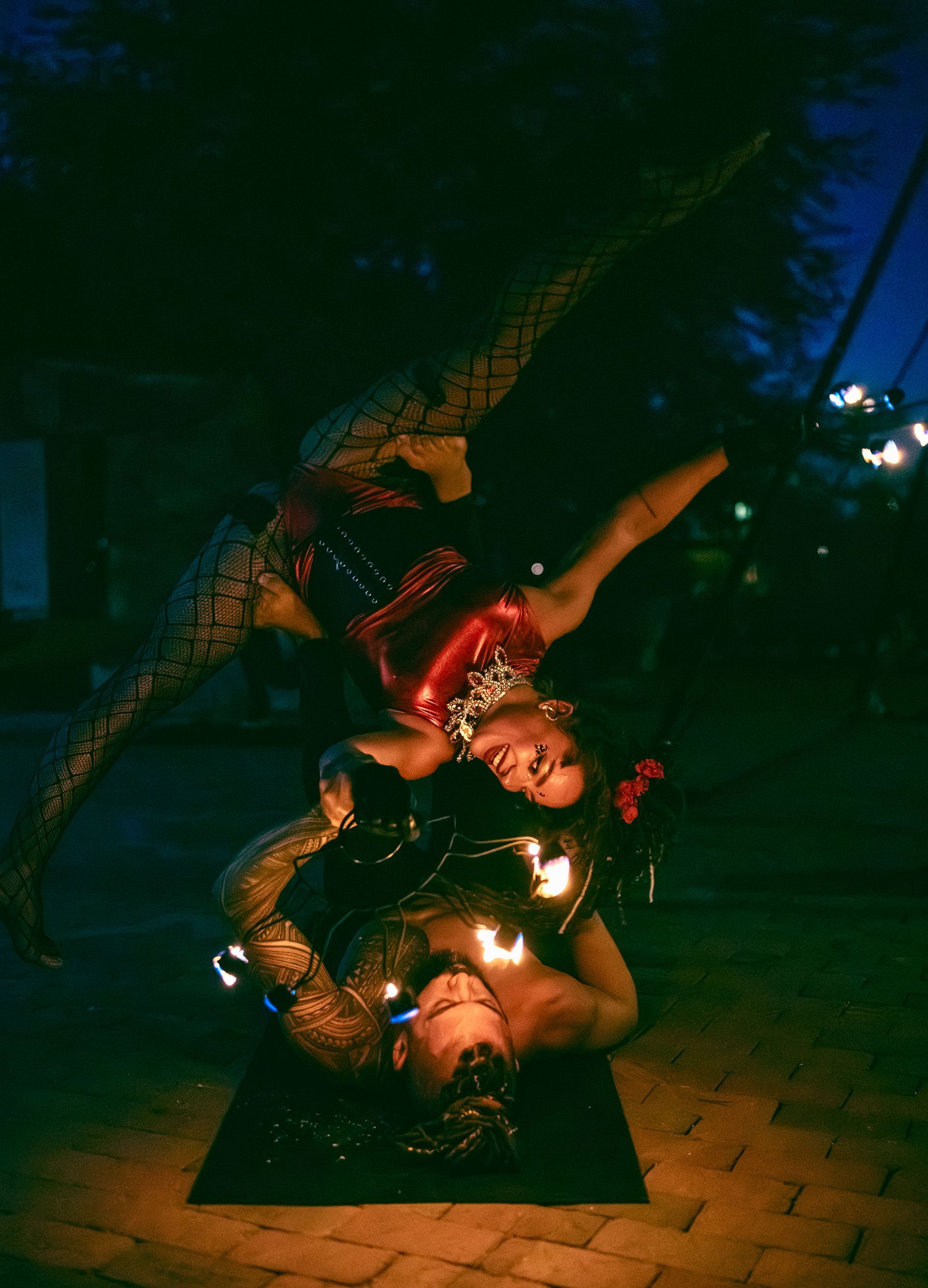 A man and a woman are doing aerial acrobatics with fire.