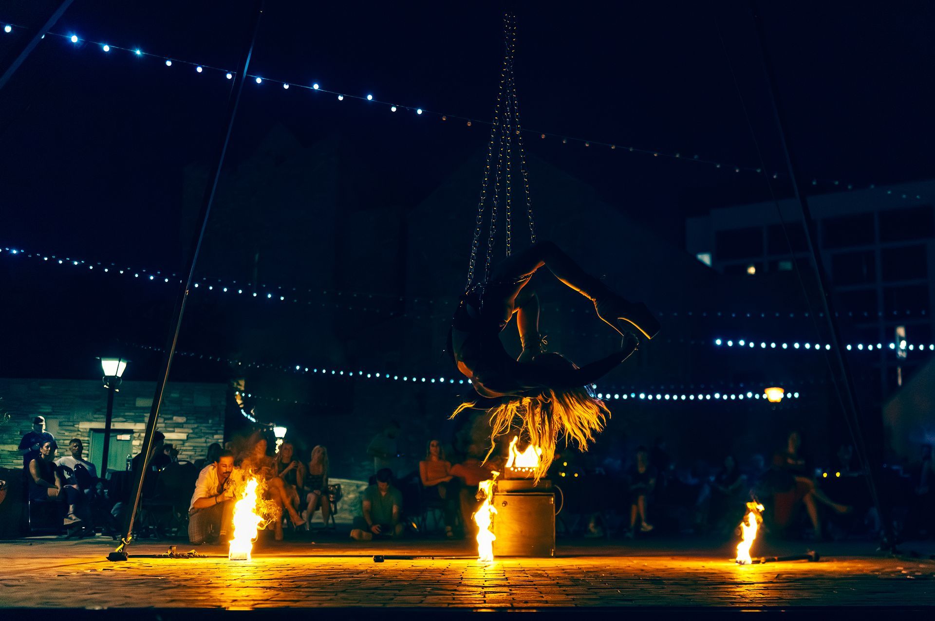 A group of people are sitting around a fire pit at night.