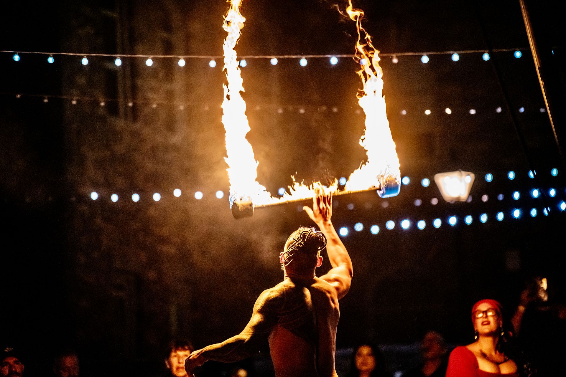 A man is holding a stick with flames coming out of it.