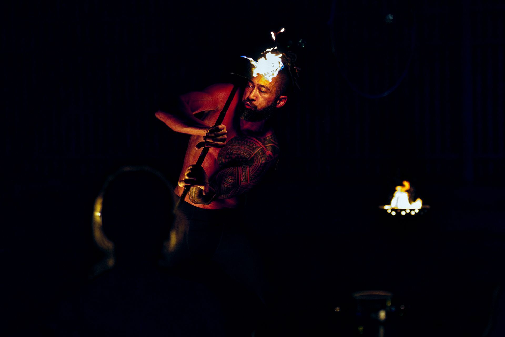 A man is playing a saxophone in the dark with flames coming out of his head.