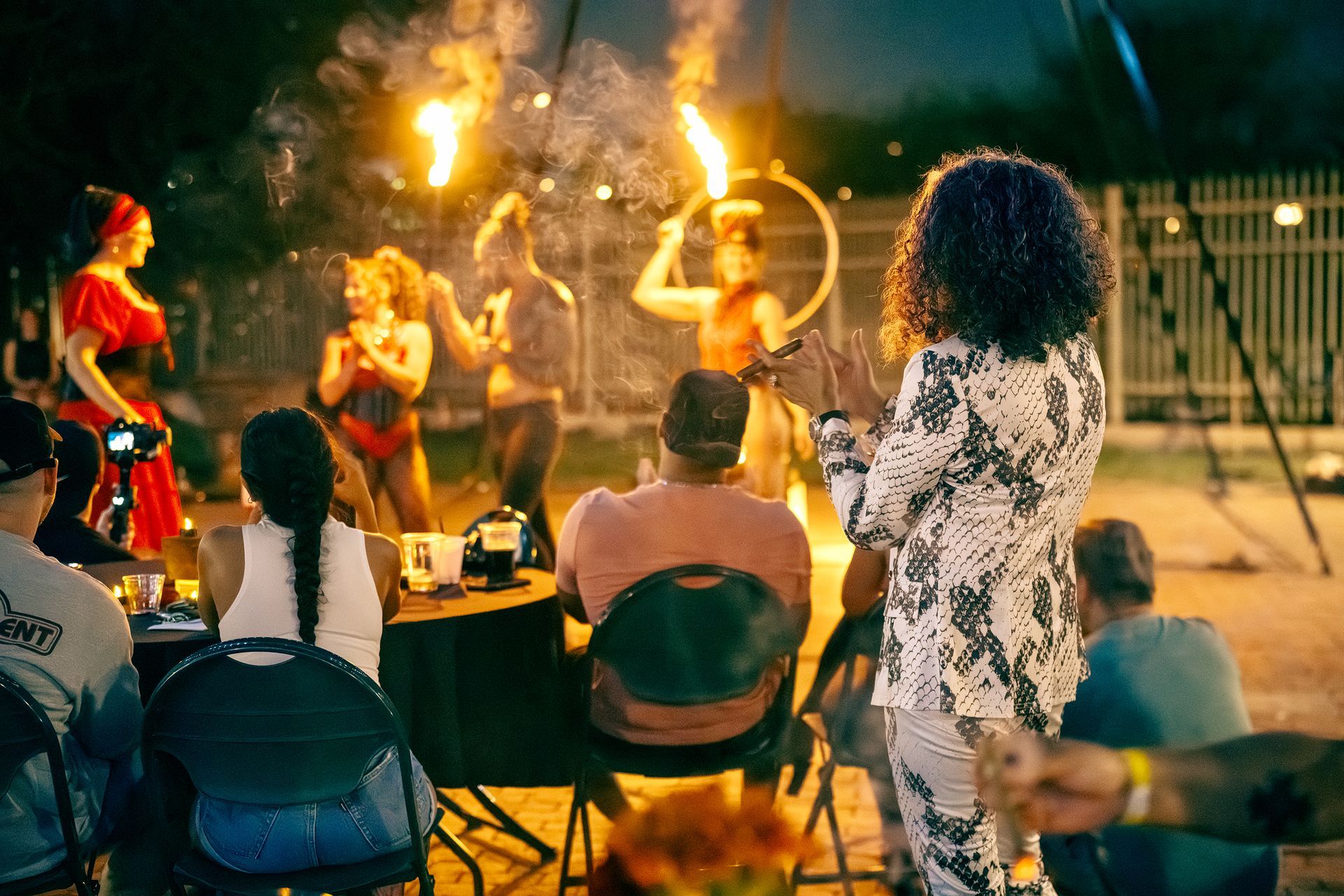 A group of people are sitting at a table watching a fire show.
