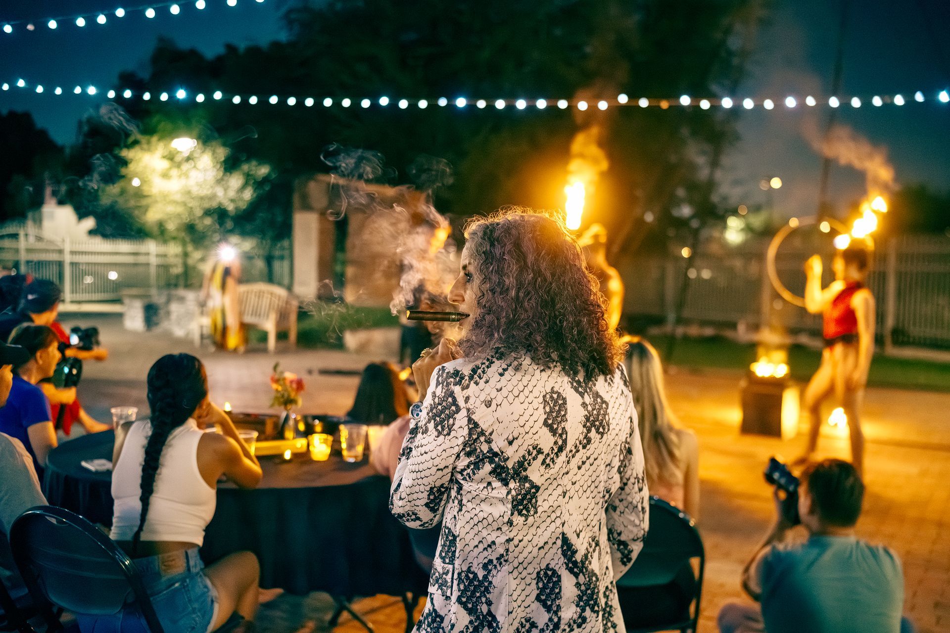 A group of people are sitting at tables watching a fire show.