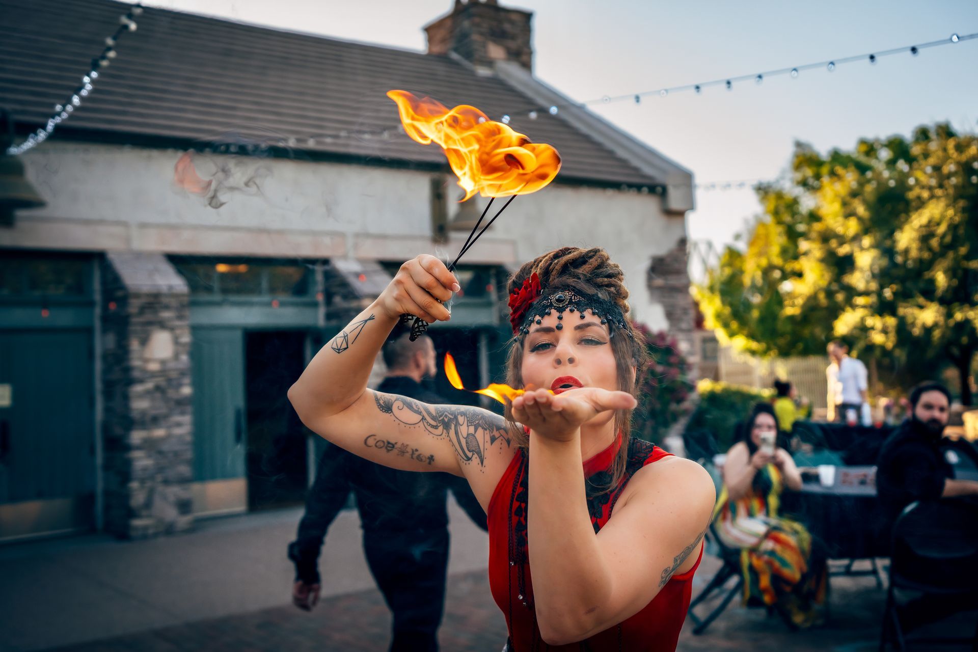 A woman is blowing a kiss while holding a stick of fire.