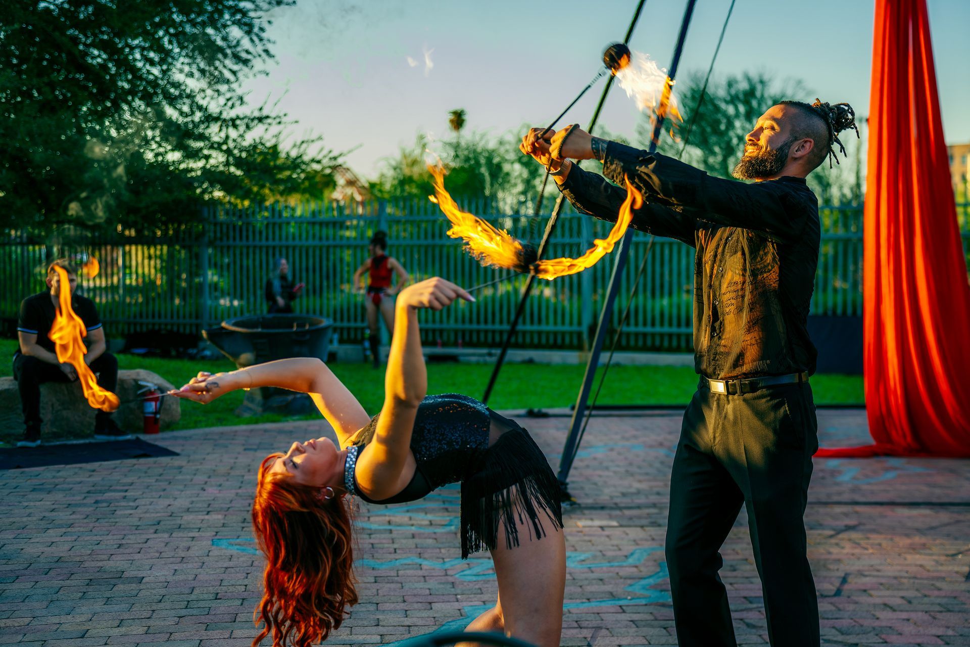 A man and a woman are performing aerial acrobatics with fire.