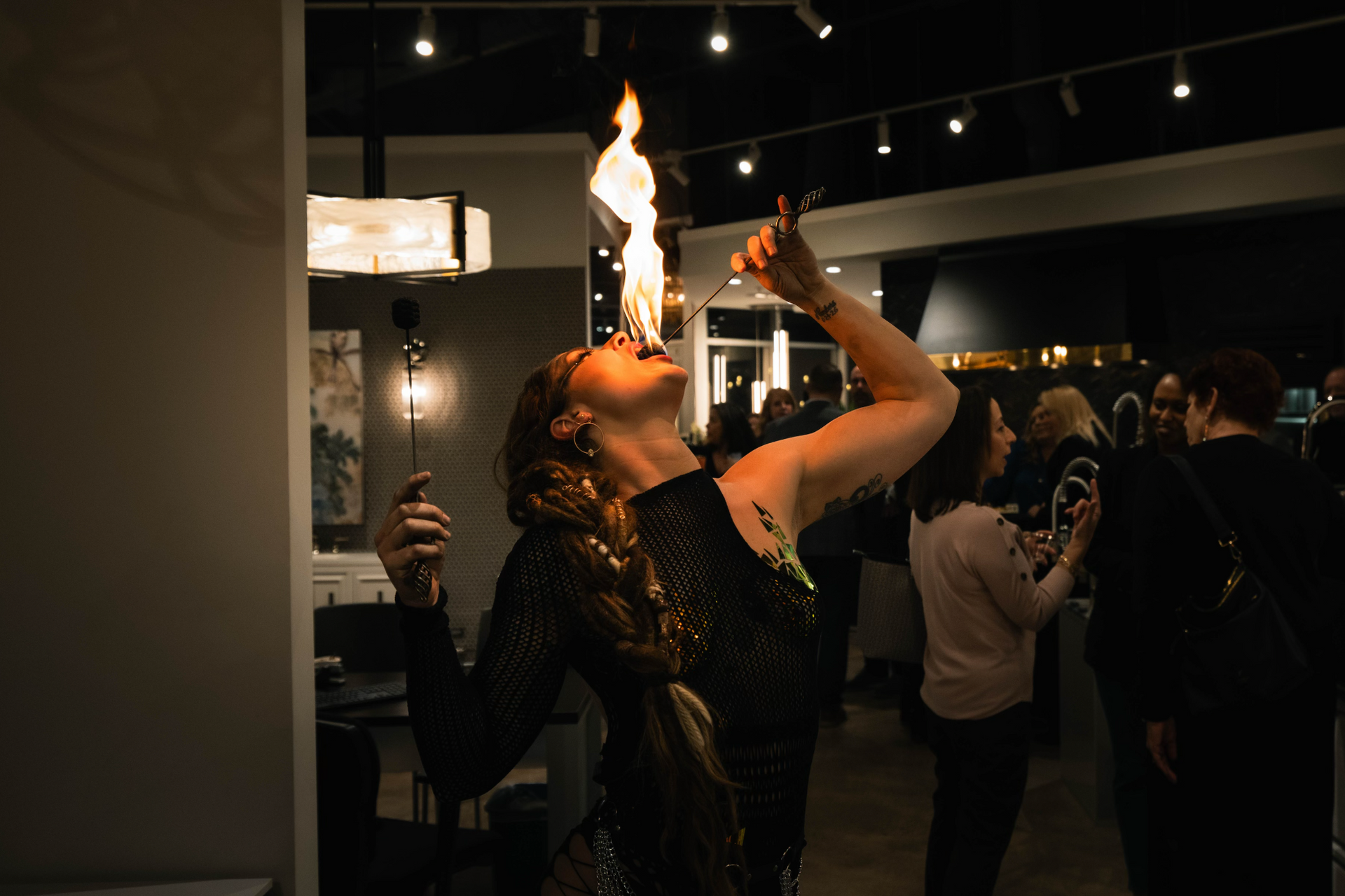 A woman eating fire indoors.