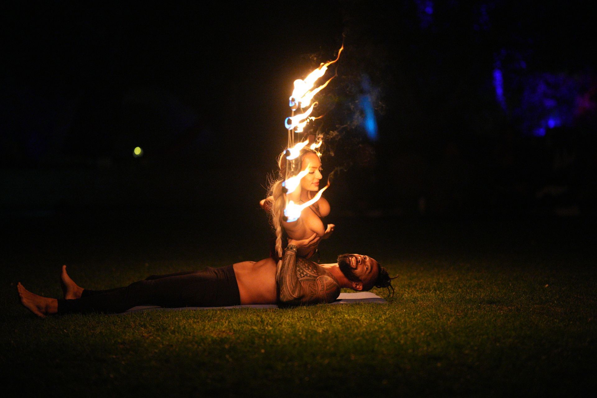A man is laying on a yoga mat with fire coming out of his mouth.