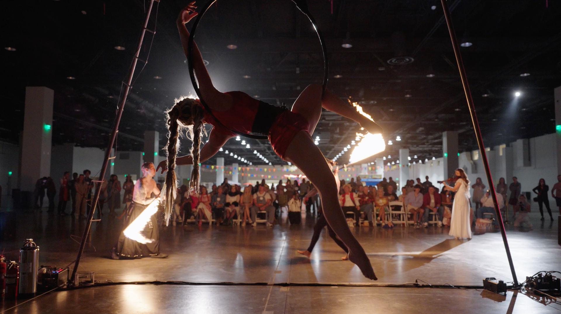 A woman is performing aerial acrobatics in front of a crowd.