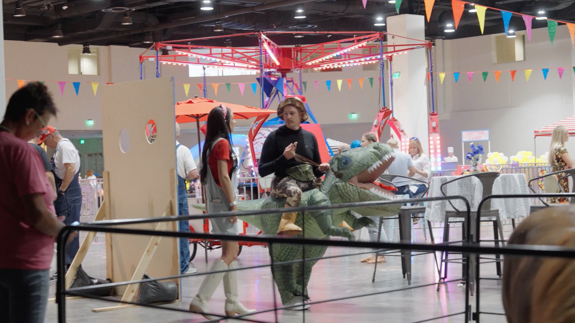 A group of people are standing around a carousel at a carnival.
