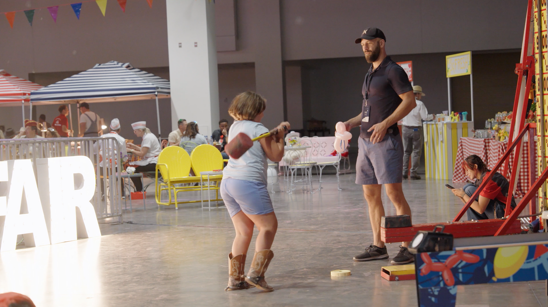 A man and a little girl are playing a game at an amusement park.