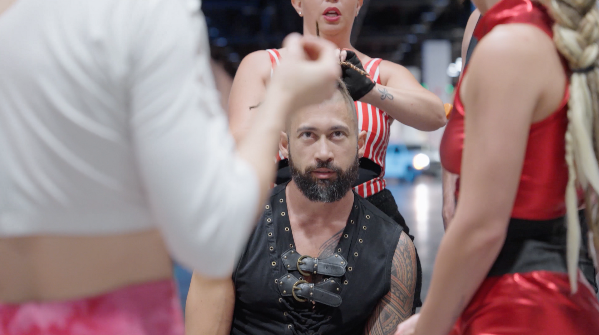 A man with a beard is sitting in a chair surrounded by women.