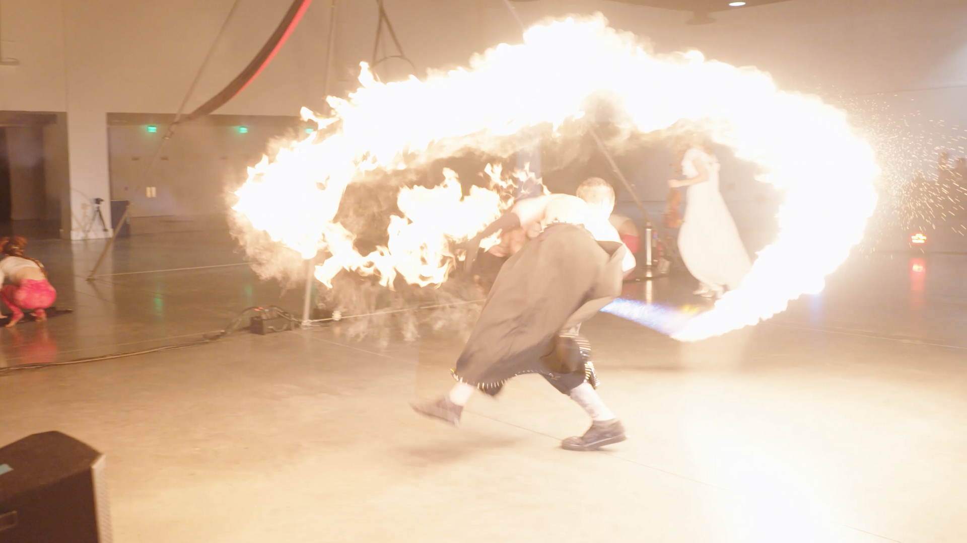 A man is standing in front of a fireball in a dark room.