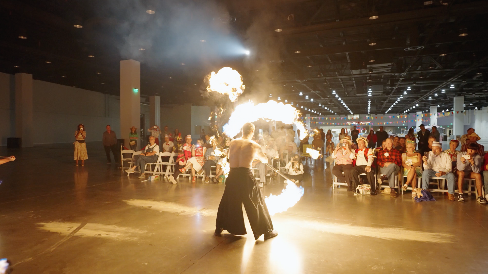 A man is holding a fireball in front of a crowd of people.