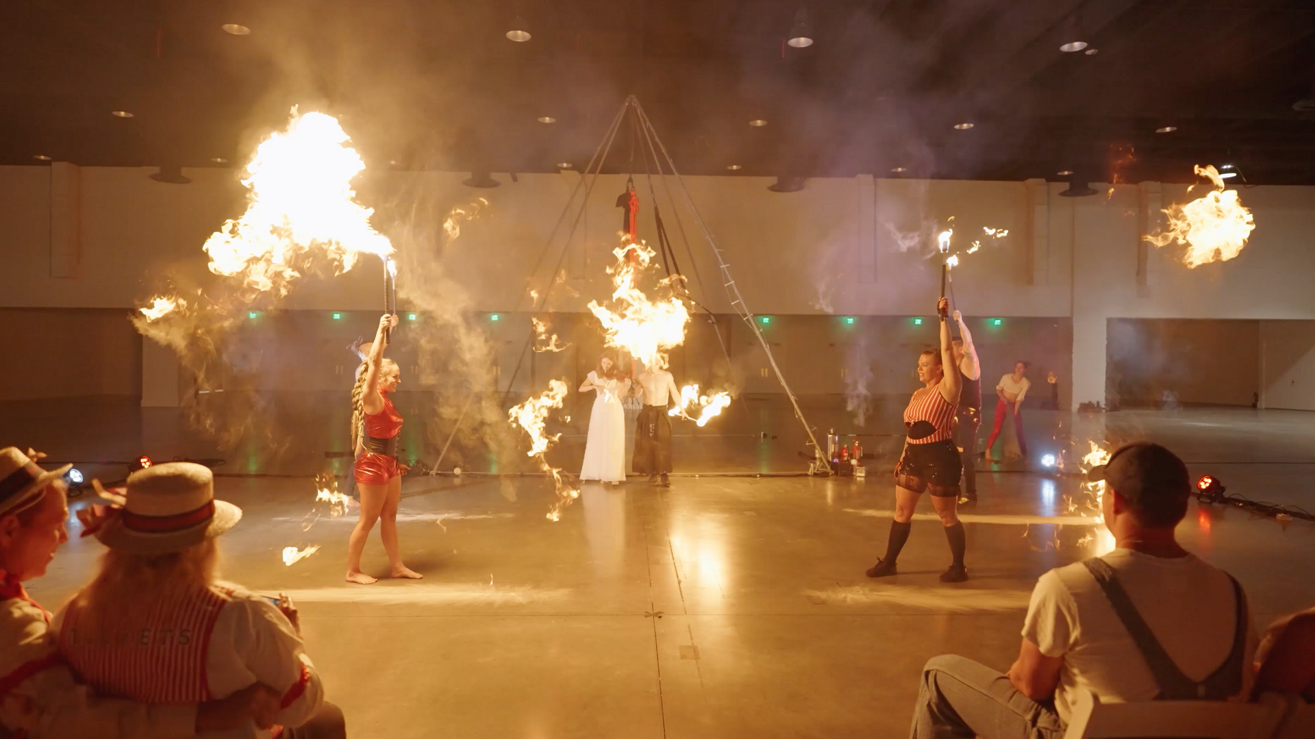 A group of people are watching a fire show in a large room.