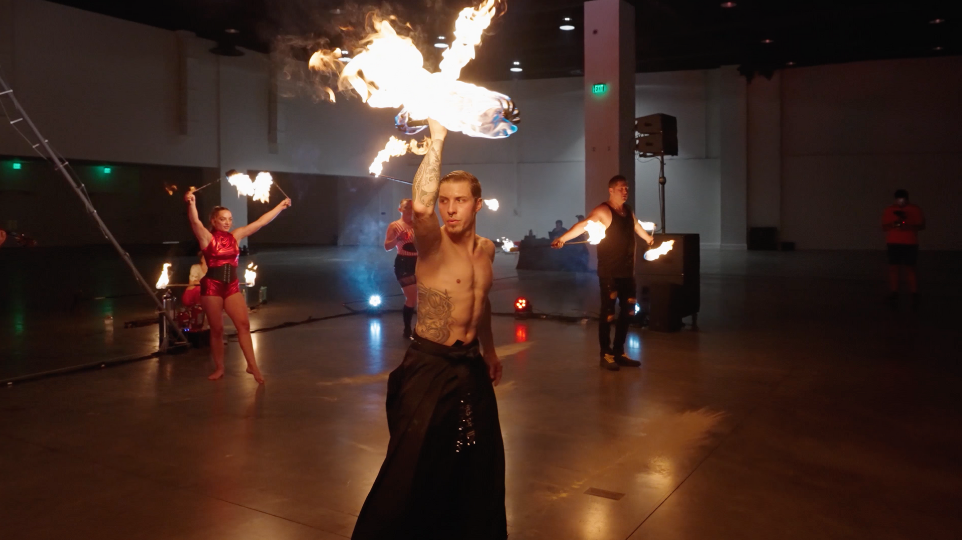 A group of people are dancing with fire in a large room.