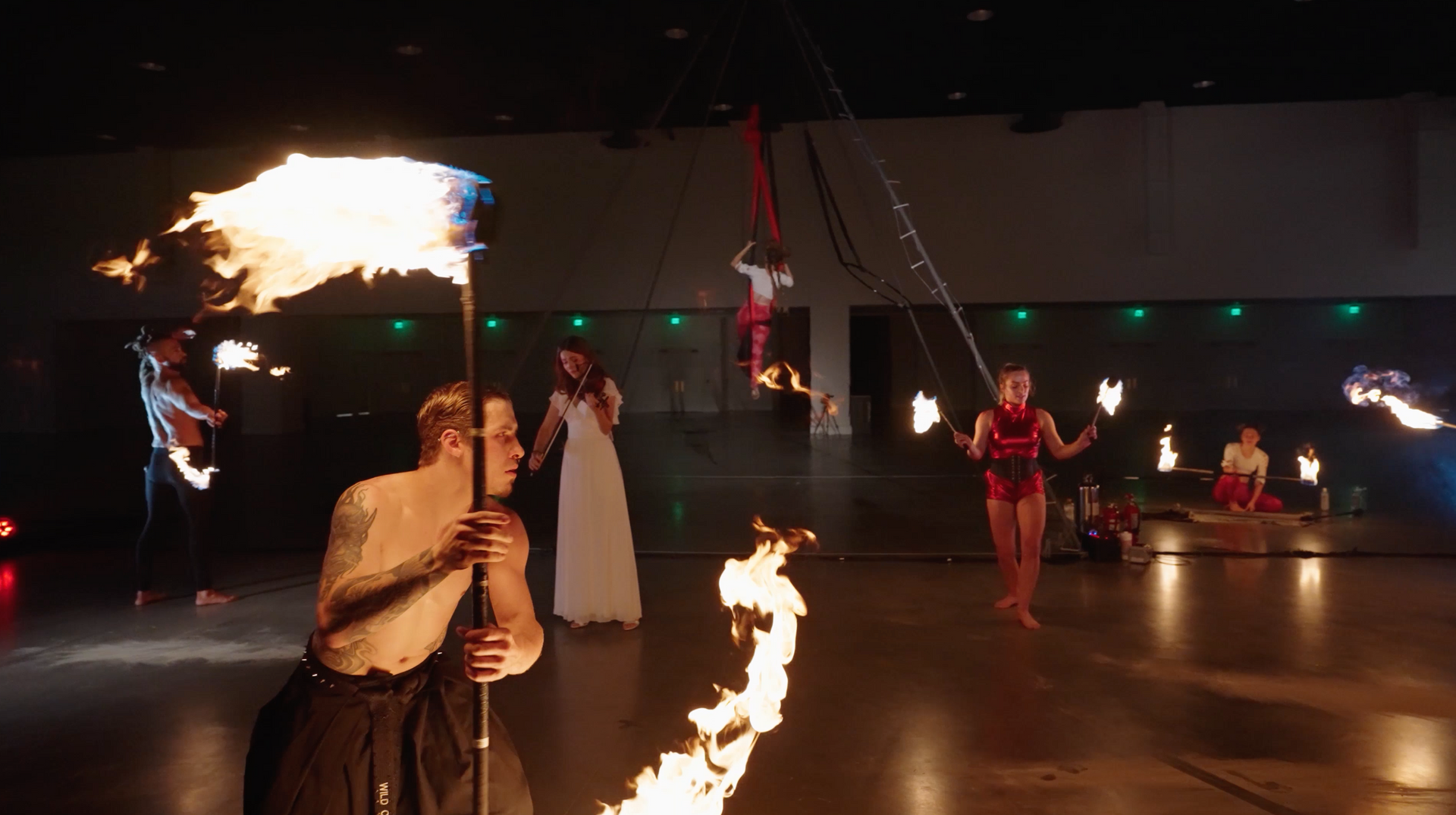 A group of people are performing a fire show in a dance studio.