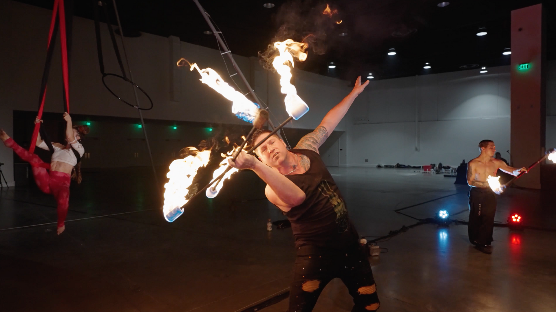 A group of people are performing a fire show in a room.