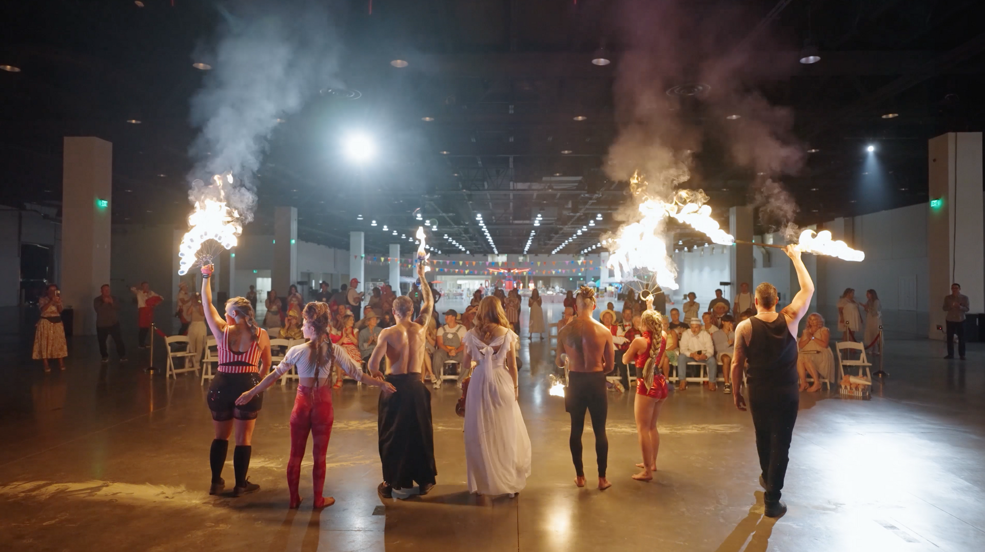 A group of people are holding fireworks in a large room.