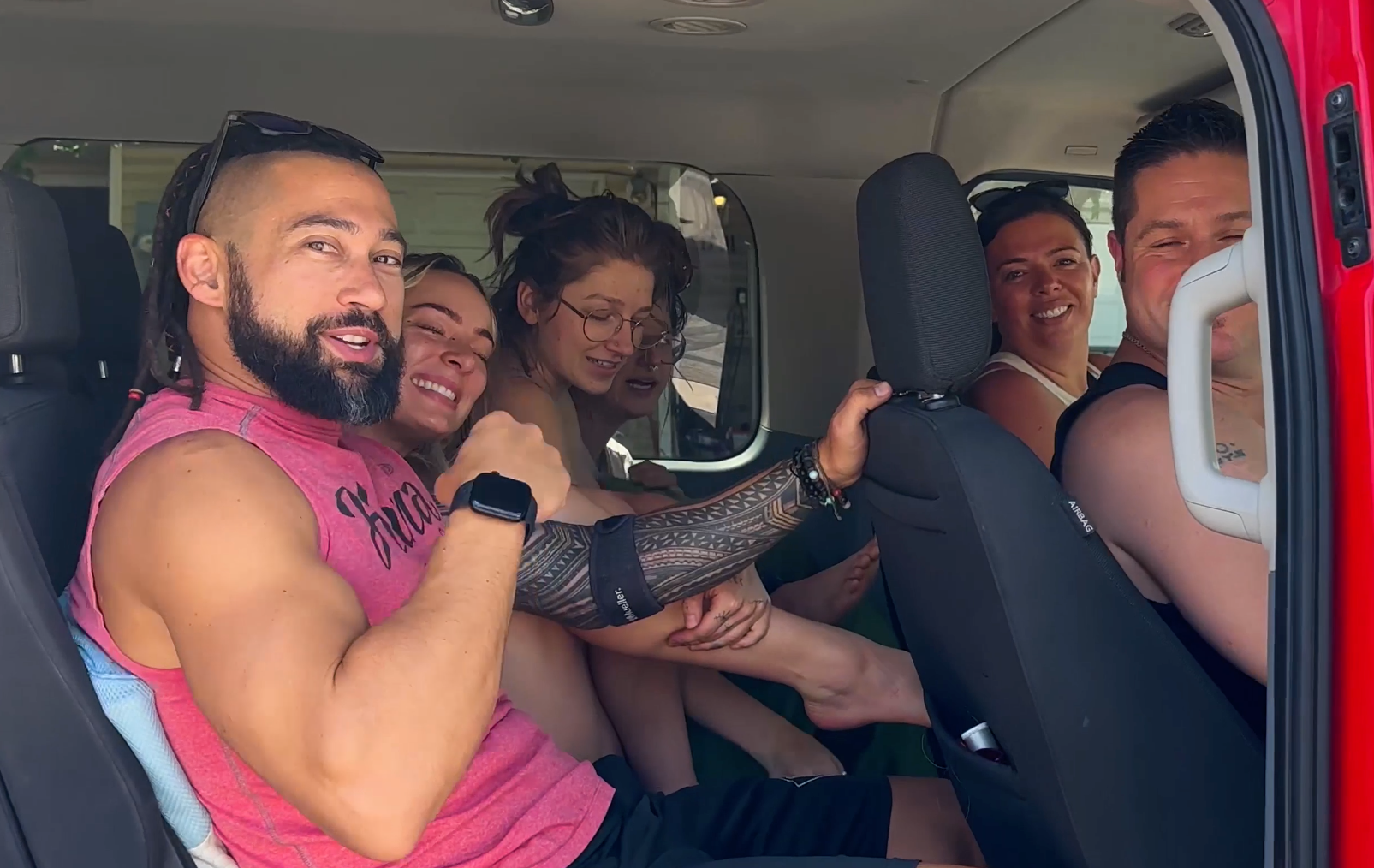A group of people are sitting in the back of a red van.