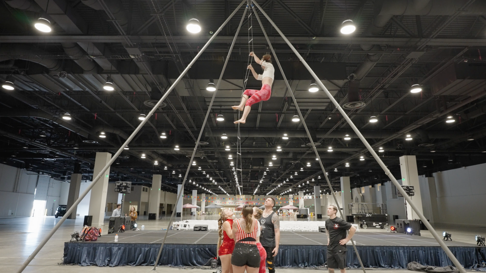 A group of people are doing aerial acrobatics in a large room.