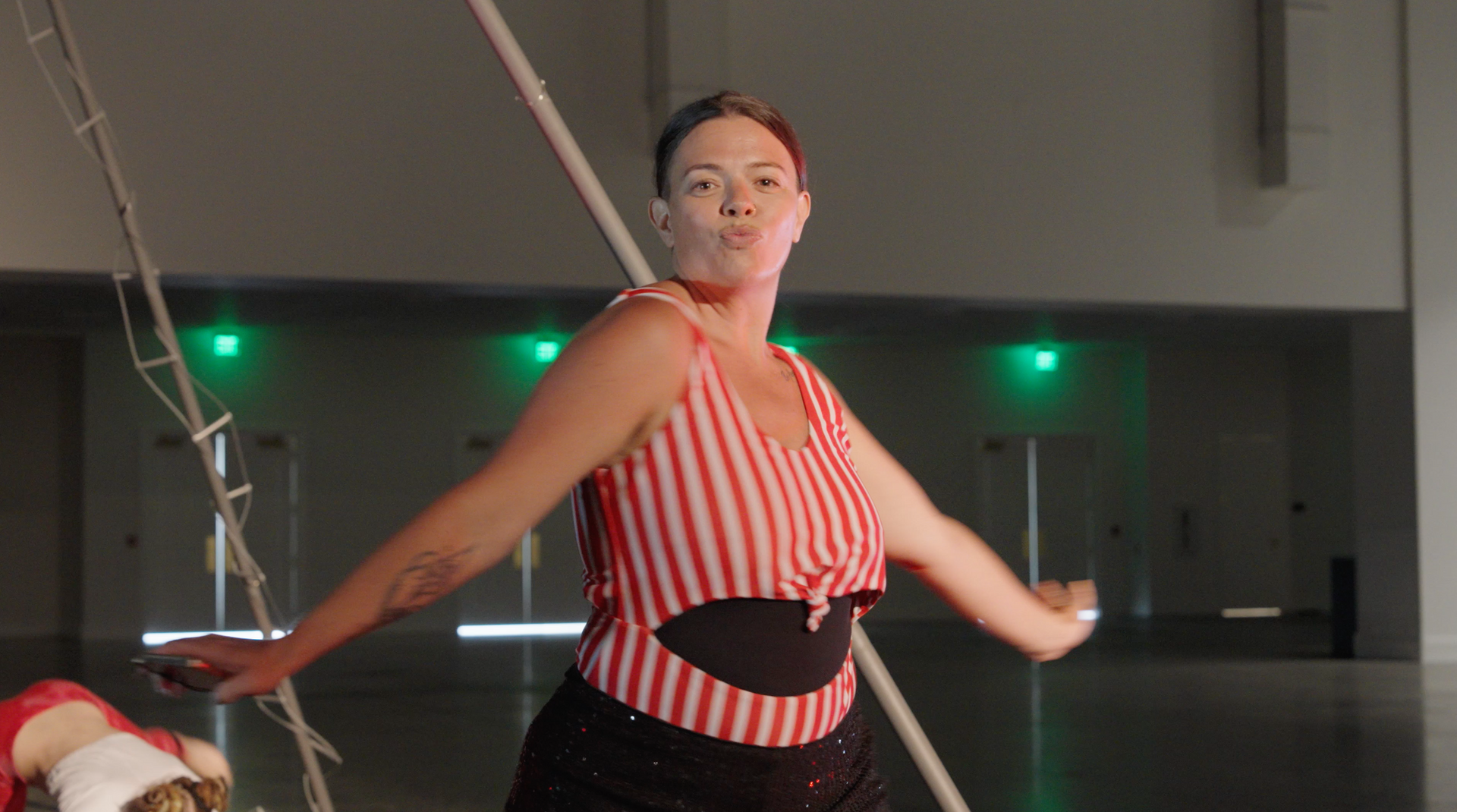 A woman in a striped top is dancing on a rope in a gym.