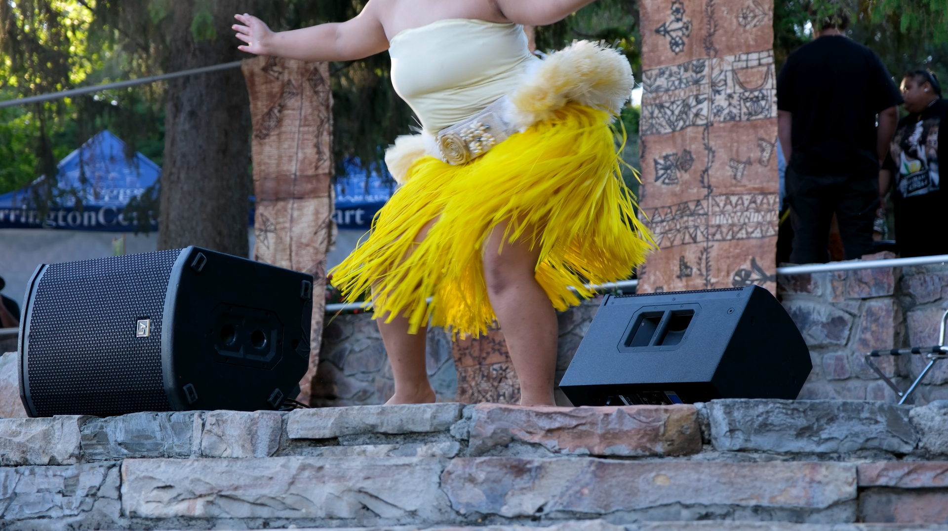 A woman in a yellow skirt is dancing on a stage