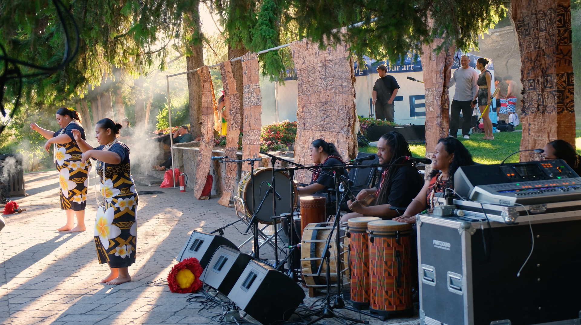 A group of people are playing drums and dancing in a park.