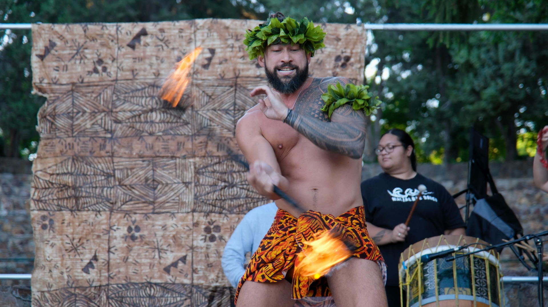 A shirtless man is holding a fire stick in his hand.