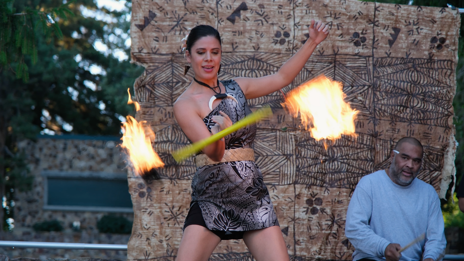 A woman is holding a hula hoop with flames coming out of it.