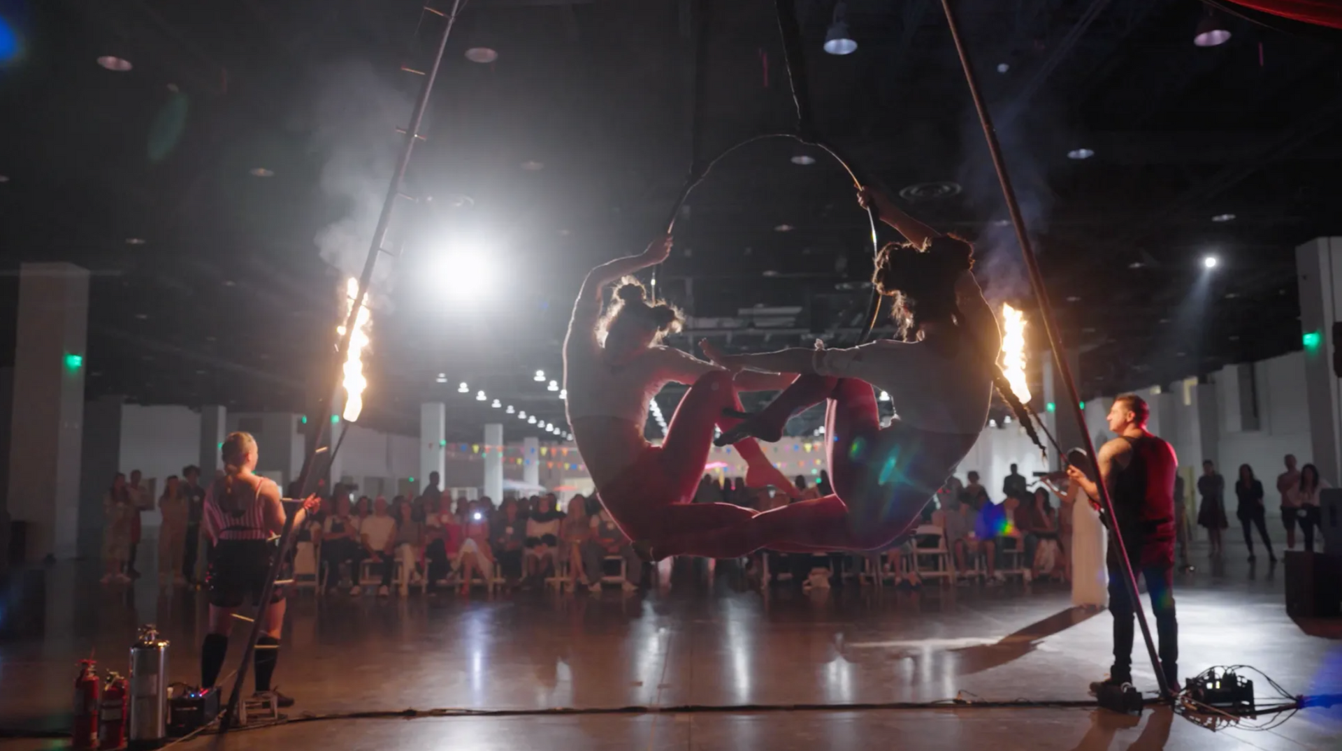 A group of people are performing aerial acrobatics in a dark room.