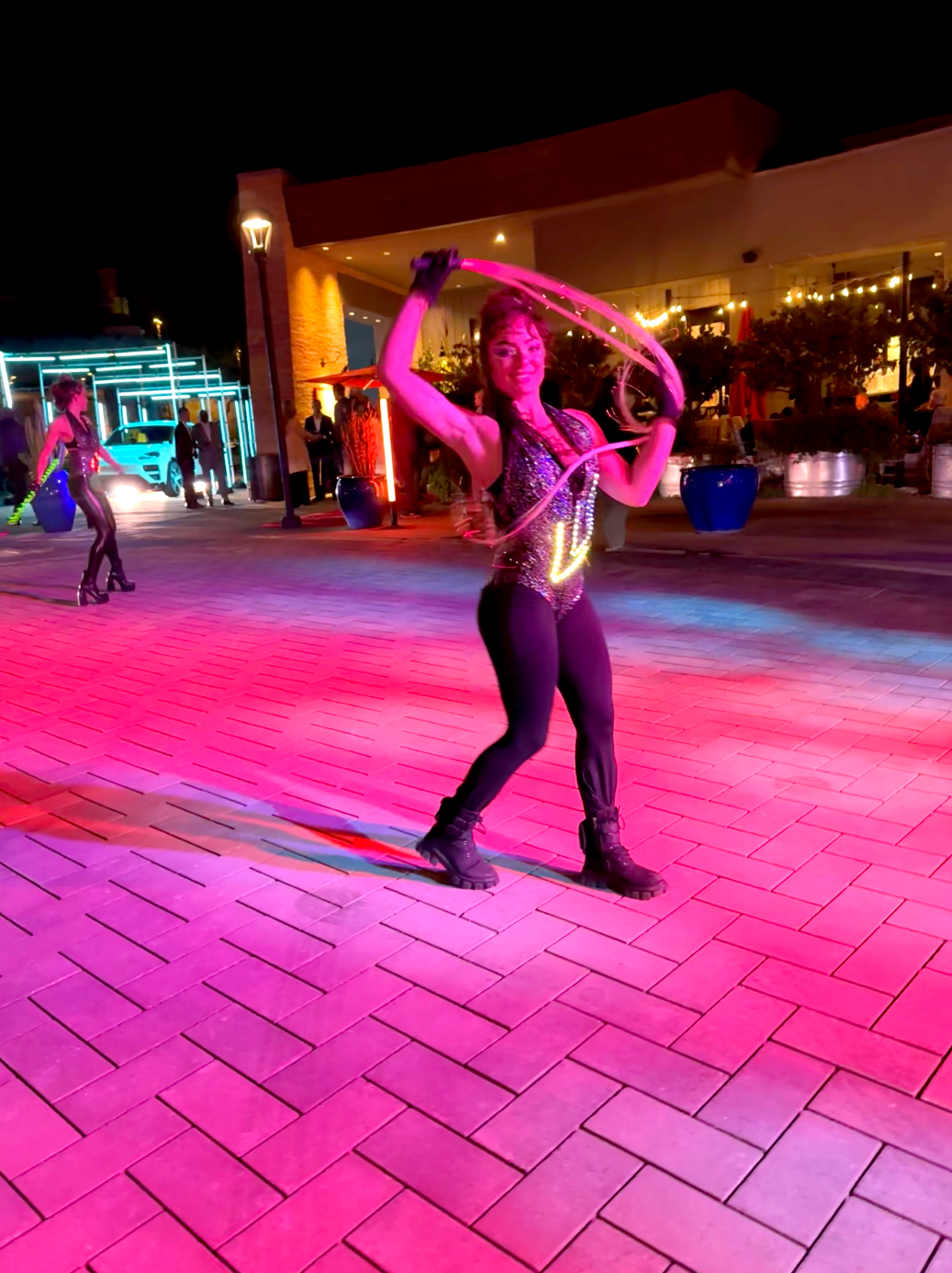 A woman is standing on a brick floor holding a hula hoop.