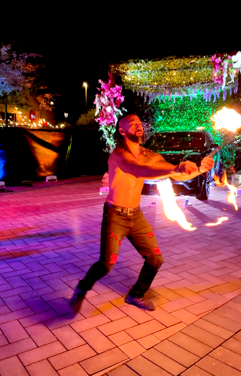 A shirtless man is holding a fire stick in his hands.