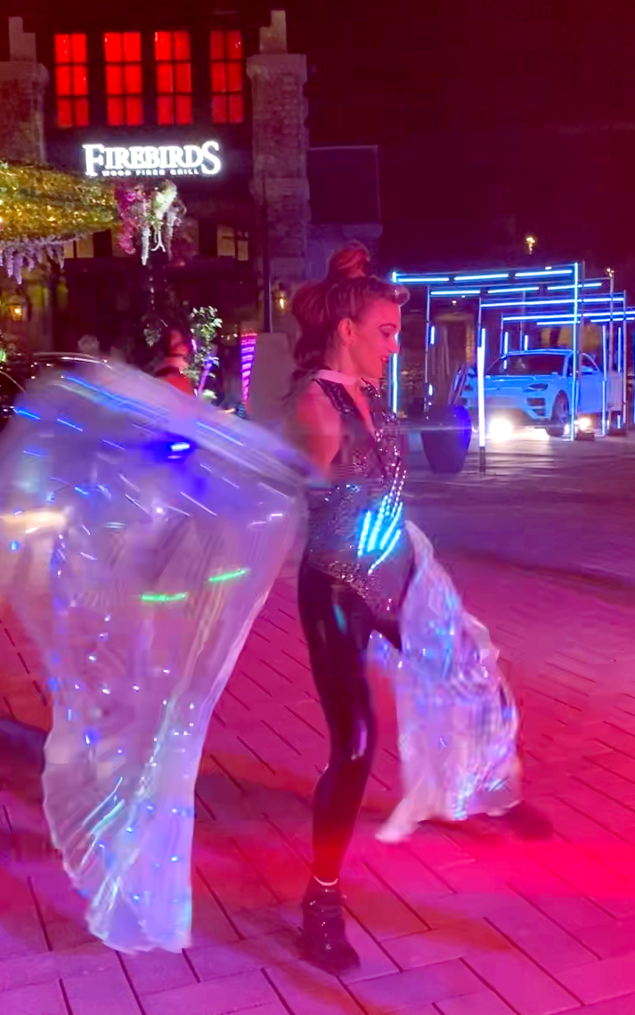 A woman is dancing in front of a building that says freddy 's.