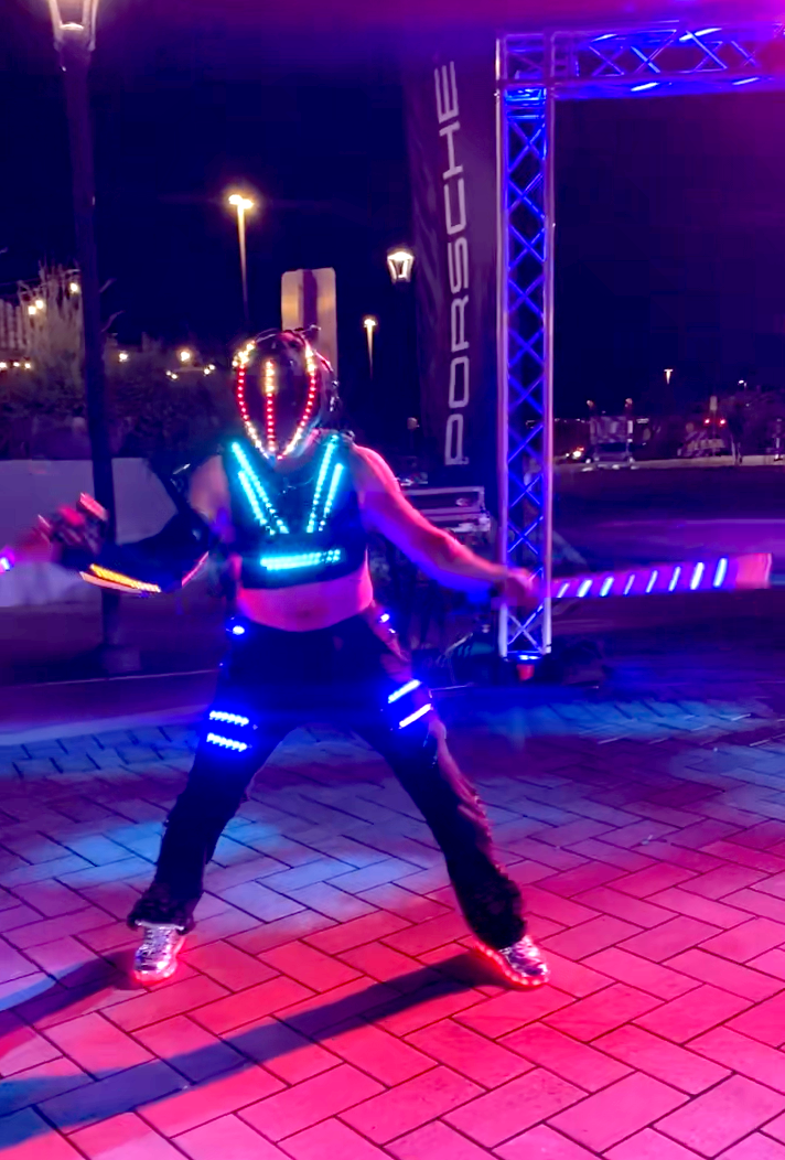A person is dancing in front of a porsche sign