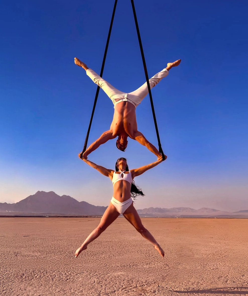 A group of people are dancing in a dark room with smoke coming out of the ceiling.