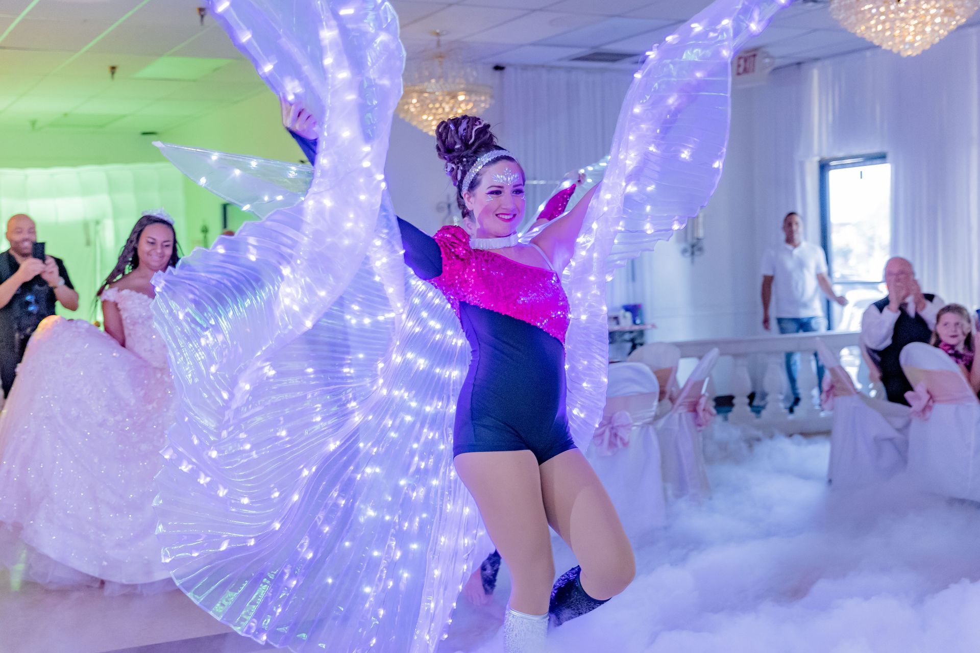 A woman is dancing in a room with lights on her wings.