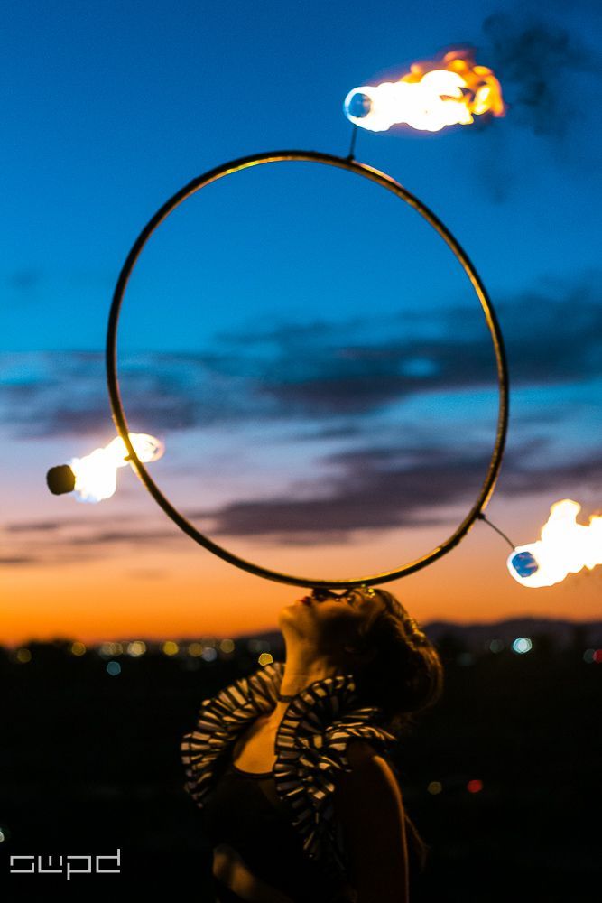 A woman is holding a hoop with fire coming out of it