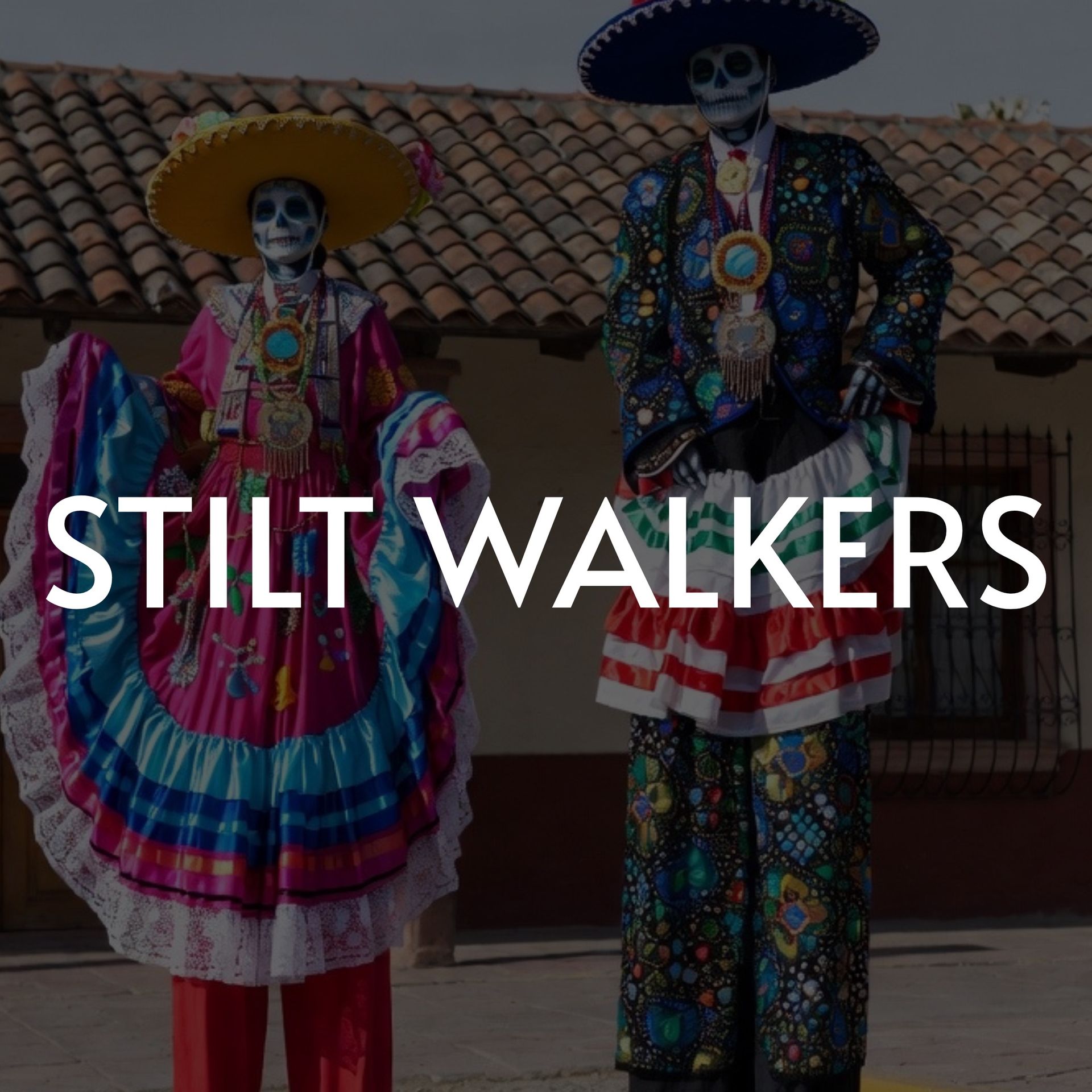 Two stilt walkers in colorful Día de Muertos costumes; the background is a building with red tile roof.