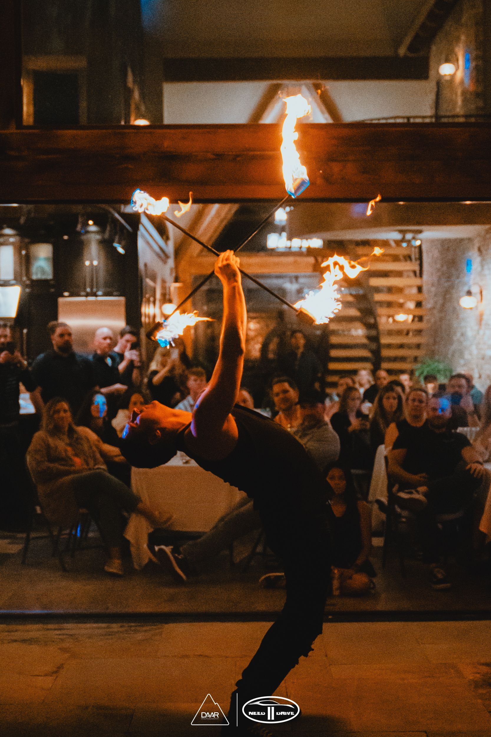 A man is doing a trick with a fire stick in front of a crowd of people.