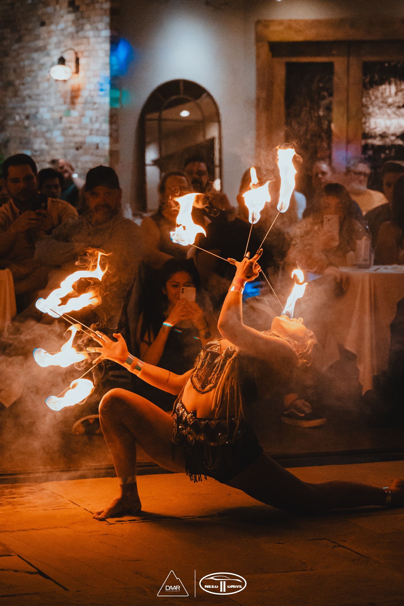 A woman is performing a fire show in front of a crowd.