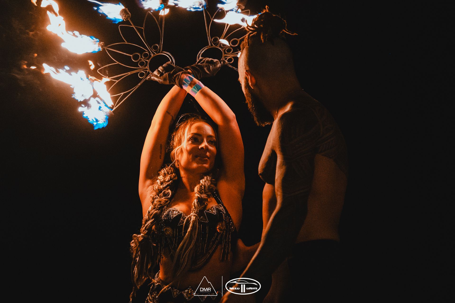 A man and a woman are dancing with fire in the dark.