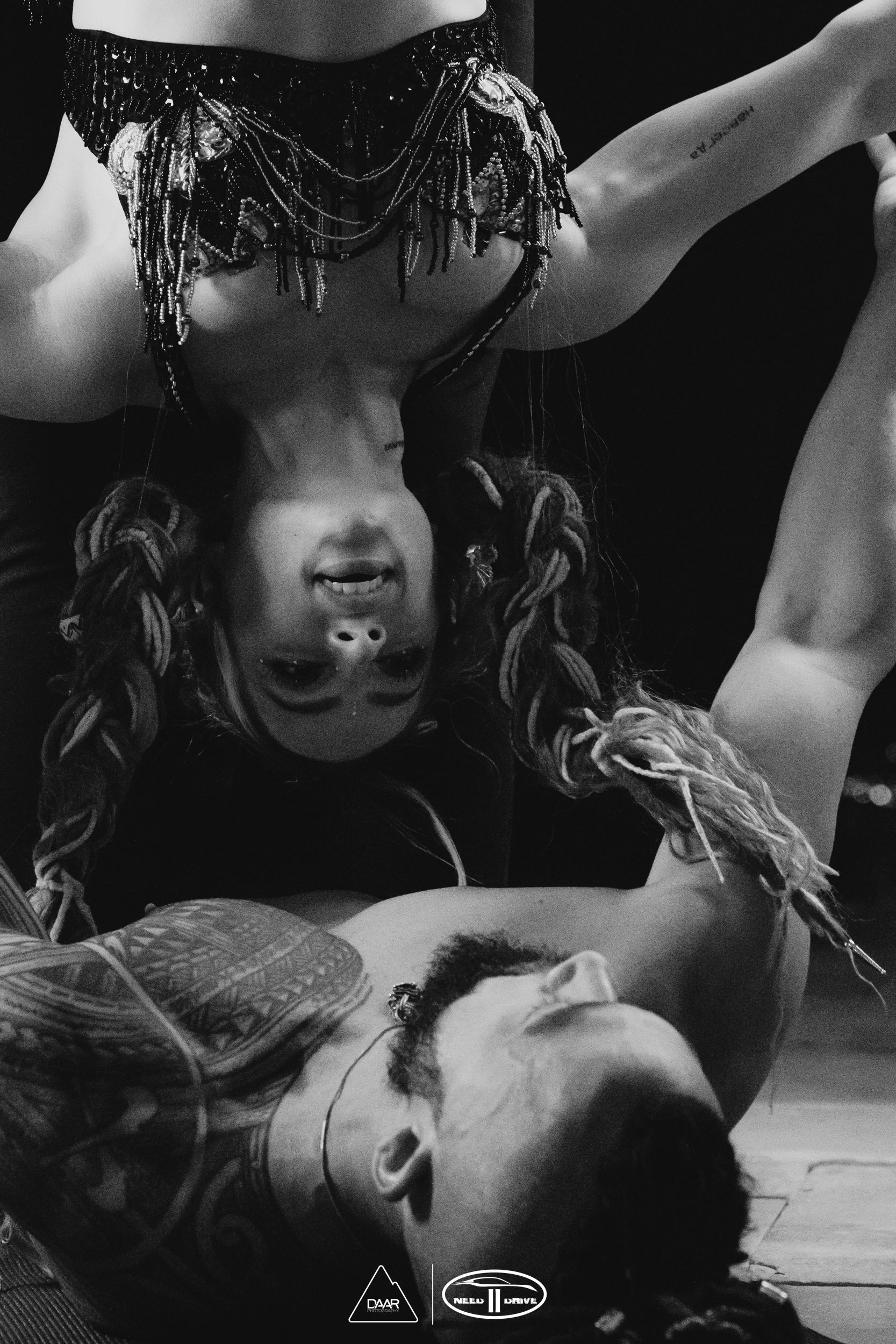 An upside down woman performing acrobatic fire with a man.