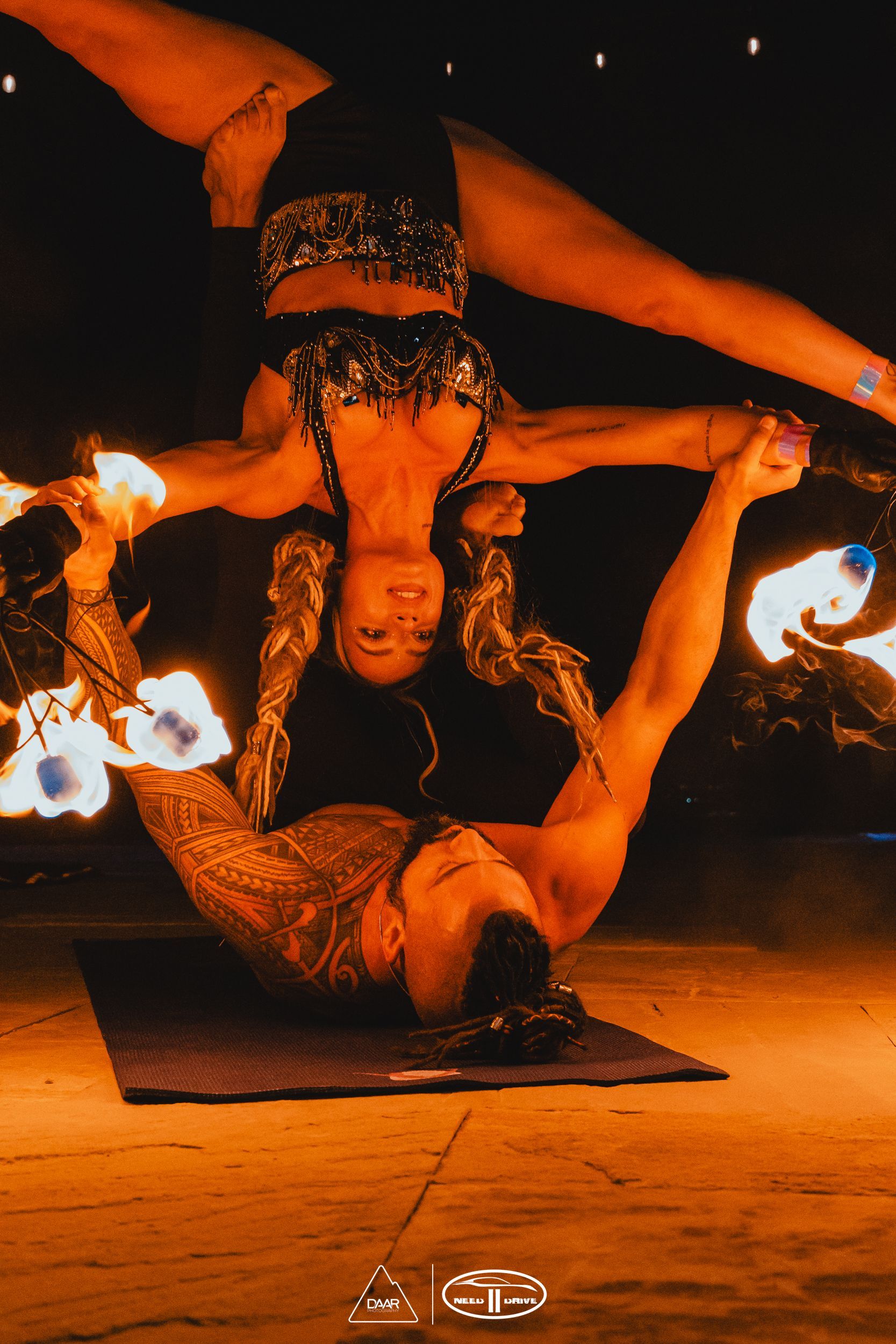 A man and a woman are doing a handstand with fire.