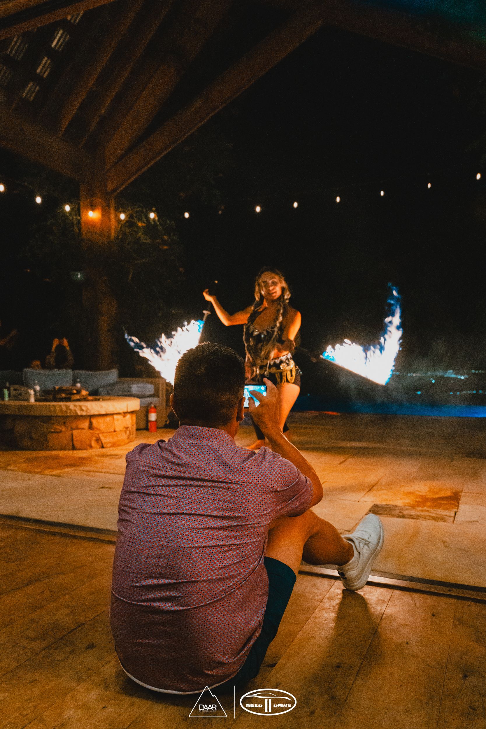 A man is taking a picture of a woman dancing with fire.