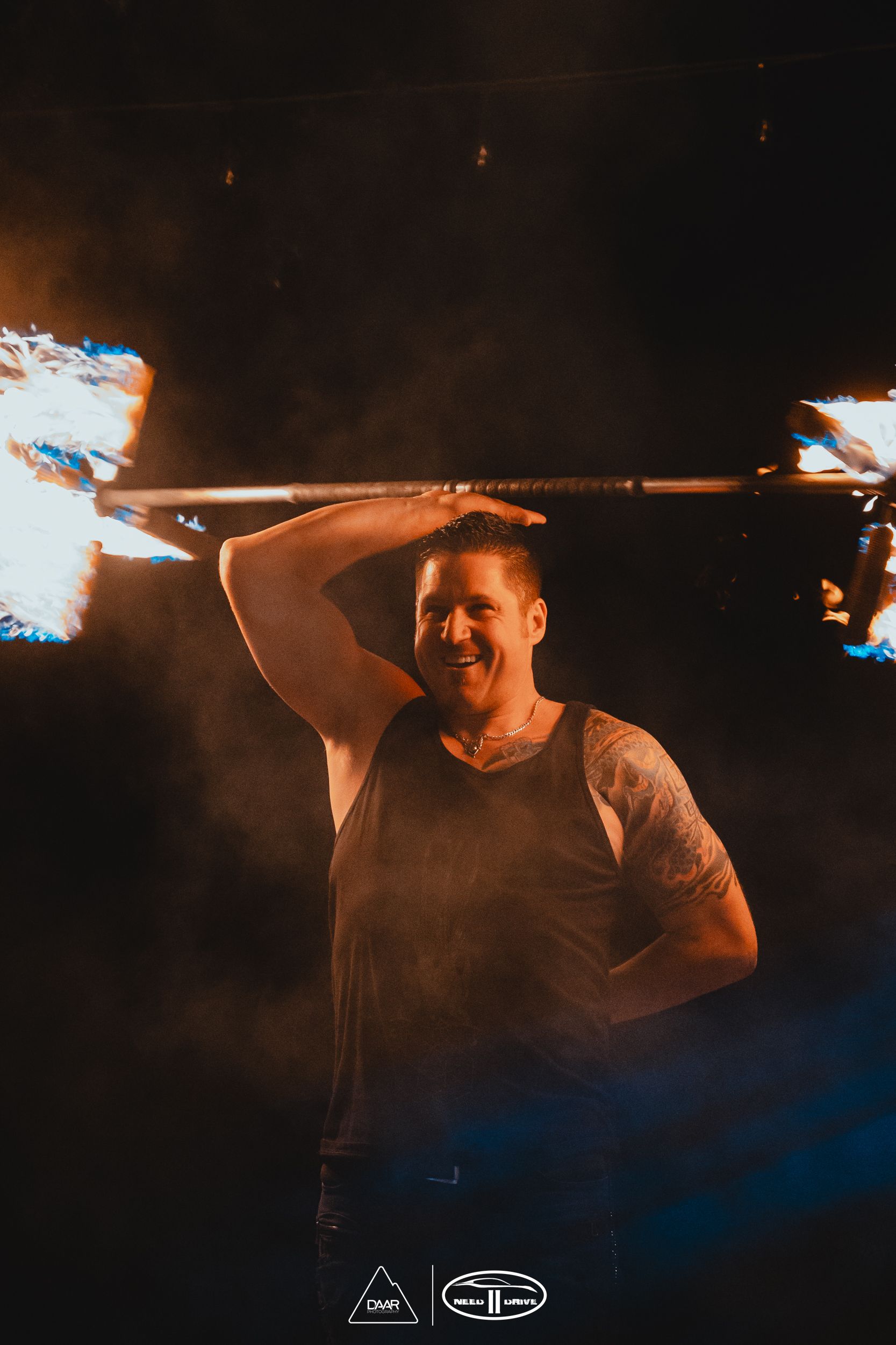 A man is holding a torch over his head in the dark.