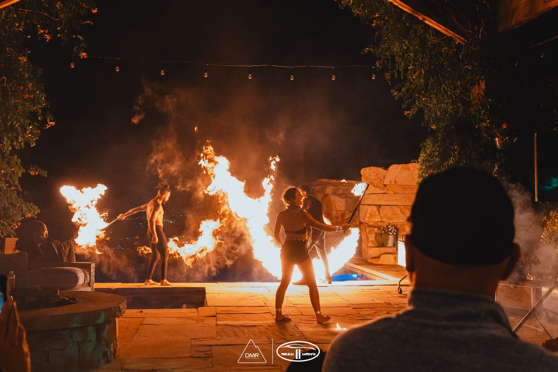A man is watching a fire show at night.