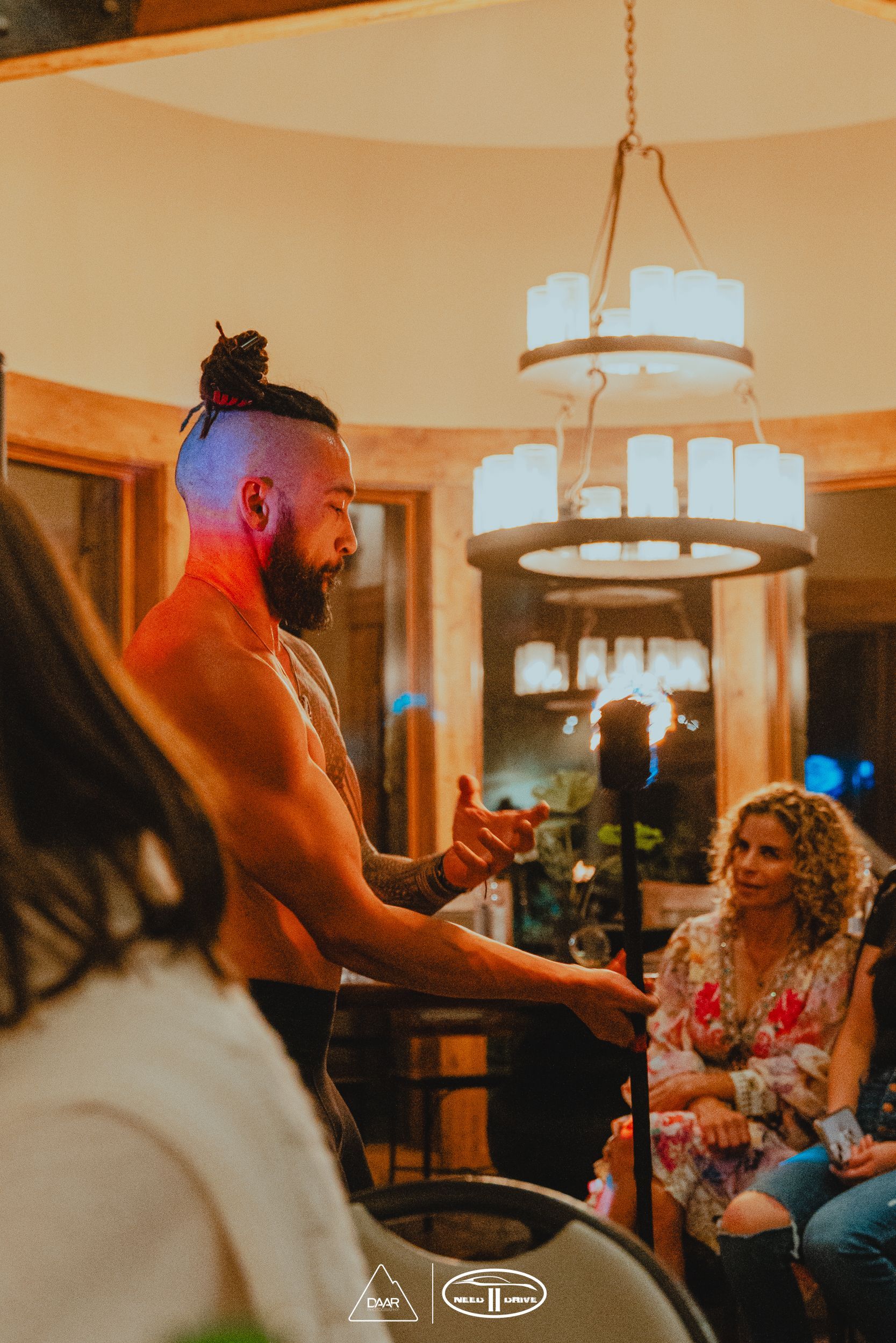 A shirtless man is standing in front of a group of people.