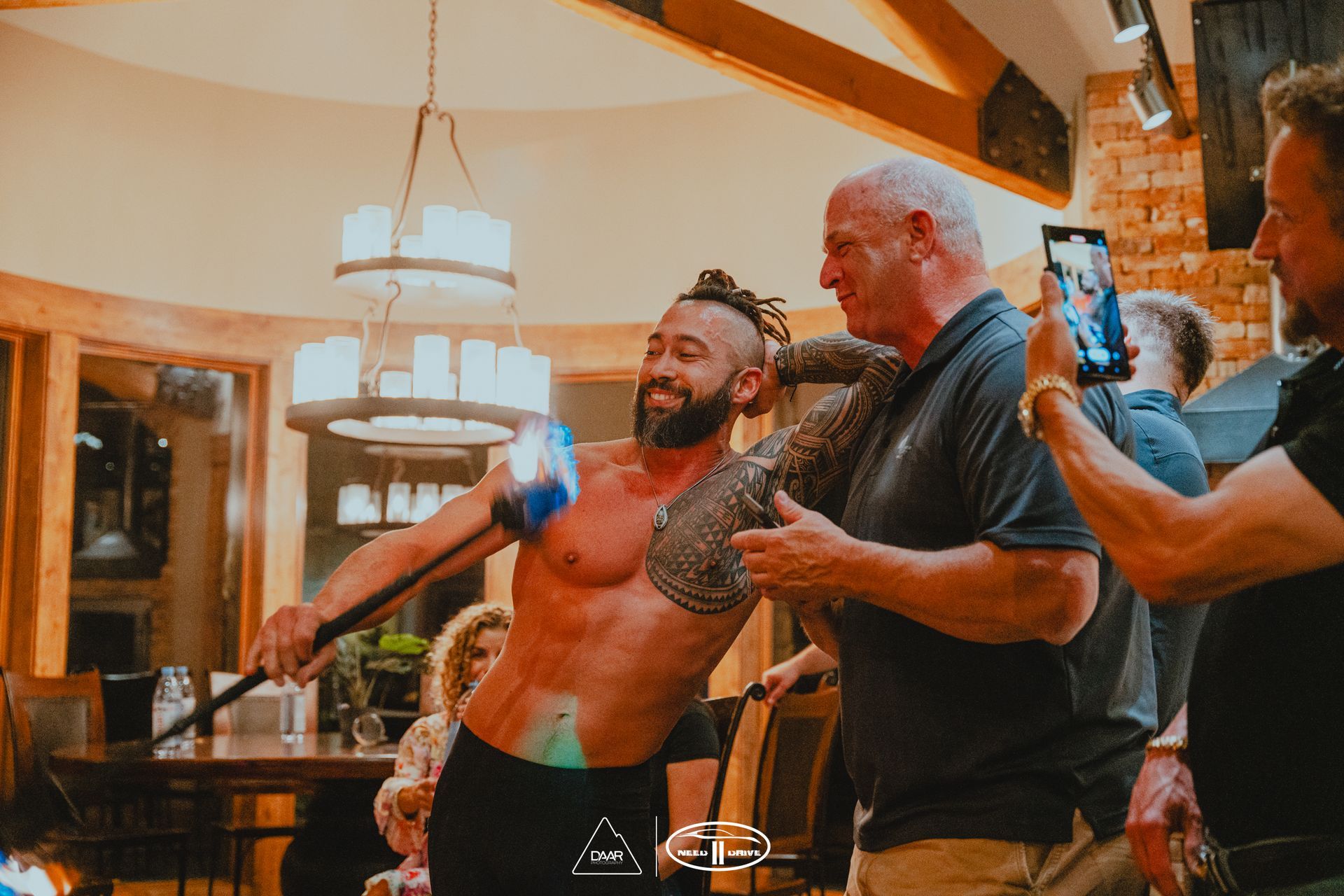 A group of men are standing around a man without a shirt in a room.