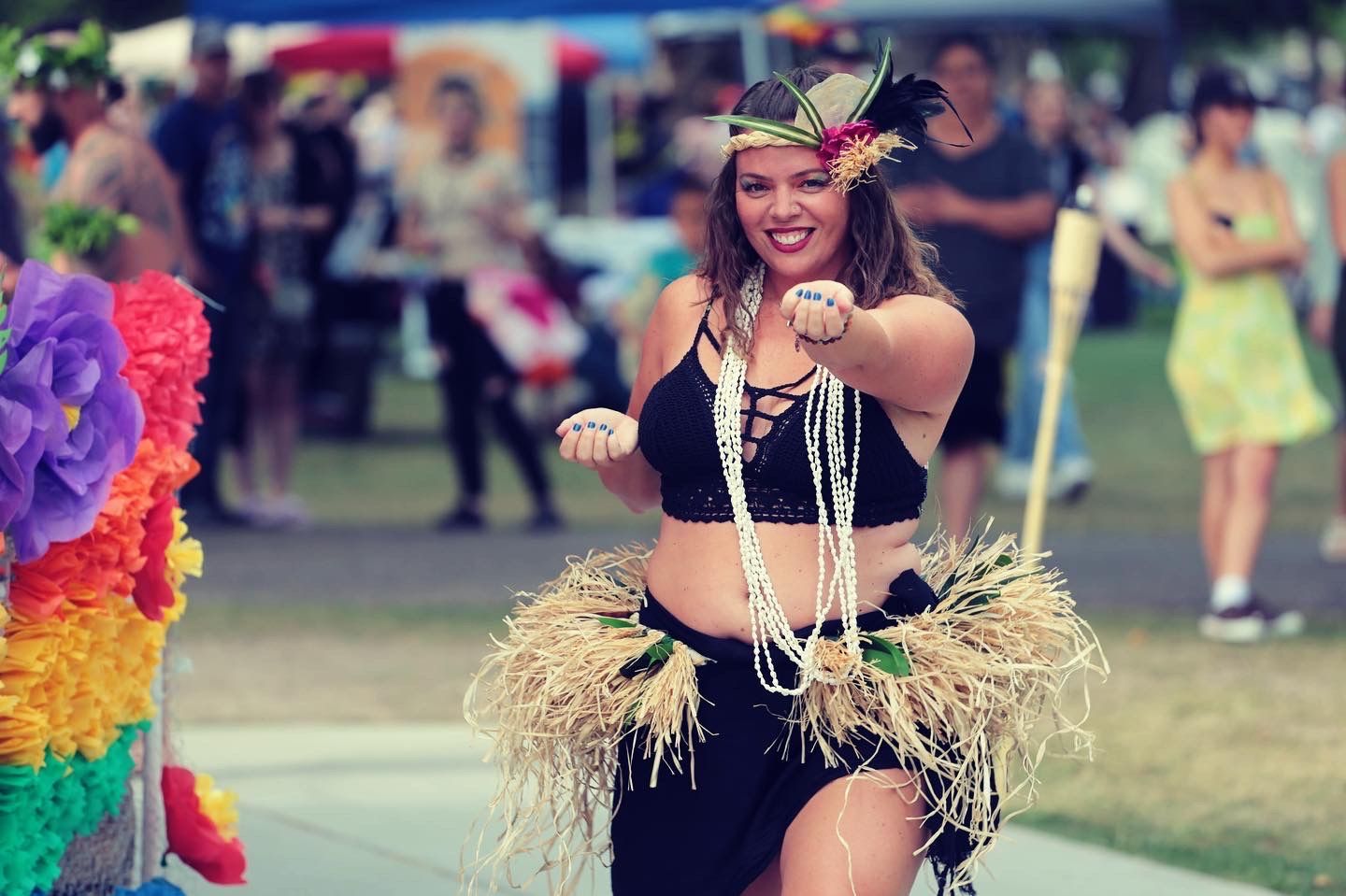 A woman in a hawaiian costume is dancing in front of a crowd.